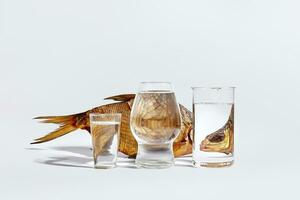 Glasses with water creating optical distortion of smoked fish on white surface photo