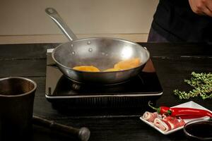 Peaches on a fry pan. Canned fruit yellow peaches, black wooden background, board. photo