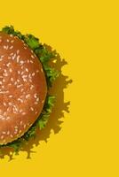 Close-up tasty fresh unhealthy hamburger with ketchup and vegetables on yellow vibrant bright background. Top View with Copy Space. photo