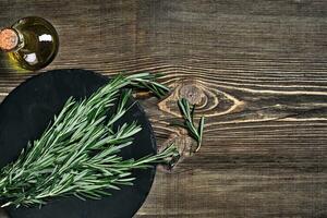 Branches of rosemary on gray wooden table. Rosemary on cutting board. Rustic style, fresh organic herbs. photo