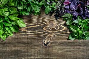 Variety of fresh organic herbs on wooden background. Freshly harvested herbs including basil, arugula. Top view. Copy space. photo