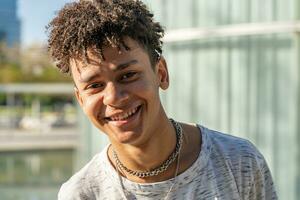 Young handsome black African American boy portrait looking at camera outdoors in the campus during a sunny day. photo