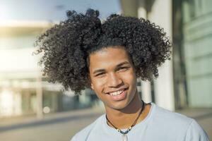 Young handsome black African American man looking at camera smiling during a sunny day. photo