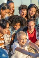 Big group of happy teenage friends taking a selfie and laughing in the city street. photo