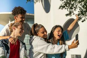 Group of happy teenage friends looking the phone and laughing in the city street. photo