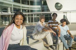 Multiethnic young students posing and looking to camera on the modern university campus during a sunny day. photo