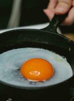 Fried egg in a frying pan, close-up of hands. photo