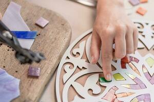 Hands of master working on new modern colorful mosaic. Close-up photo