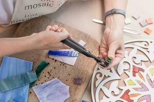 Hands of master working on new modern colorful mosaic. Close-up photo