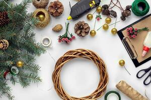 Preparing for Christmas or New Year holiday. Flat-lay of fur tree branches, wreaths, rope, scissors, craft paper over white table background, top view. photo