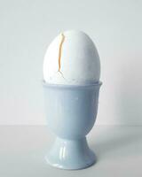 hervido huevo en un azul huevera en un blanco antecedentes. foto