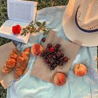 Top view of summer picnic with fruits, croissants and book photo