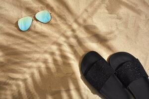 Sandal and sunglasses on a sandy background, top view photo