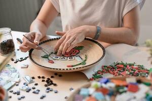 lugar de trabajo de un mosaico Maestro hembra manos tendido fuera un mosaico elemento en el mesa foto