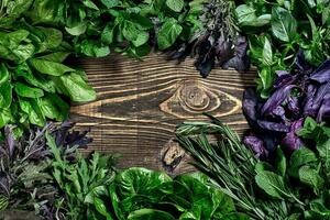 Variety of fresh organic herbs on wooden background. Freshly harvested herbs including basil, arugula. Top view. Copy space. photo