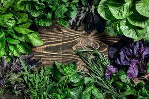 Variety of fresh organic herbs on wooden background. Freshly harvested herbs including basil, arugula. Top view. Copy space. photo