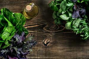 Variety of fresh organic herbs on wooden background. Freshly harvested herbs including basil, arugula. Top view. Copy space. photo