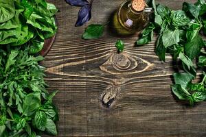 Variety of fresh organic herbs on wooden background. Freshly harvested herbs including basil, arugula. Top view. Copy space. photo