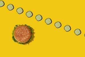 Tasty fresh unhealthy hamburger with ketchup and vegetables on yellow vibrant bright background. Top View with Copy Space. photo