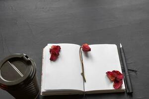 Top view of an empty notebook, scrapbook accessories and a cup of coffee on a black background. photo
