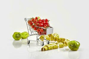 compras carretilla lleno de Tomates, pimienta en blanco antecedentes foto