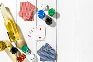 Four aces surrounded by poker chips and beer on white wooden background and copy space photo