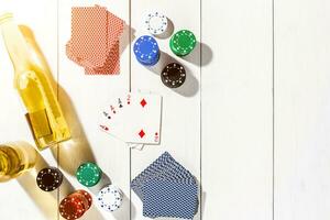 Four aces surrounded by poker chips and beer on white wooden background and copy space photo