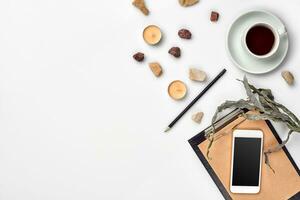 Notepad with pen and cup of tea on white table. Working space. Handmade. Top view, flat lay. photo