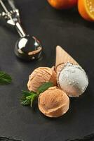 Close-up shot of a creamy and orange ice cream served on a dark slate, black background. photo