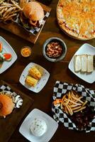 Top view of a variety of fast food on a wooden table. photo