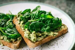 Toasts with avocado and spinach on plate. Healthy food concept. photo