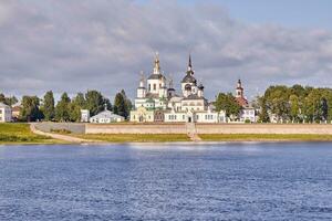 A small church and the bell tower on the banks of the river, Russia photo