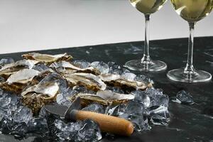 Fresh opened oysters in ice and champagne are on a black stone textured table. view with copy space. Close-up shot. photo