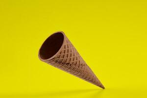 Empty, crispy wafer cone for ice cream against yellow background. Concept of food, treats. Mockup, template for your advertising and design. Close up photo