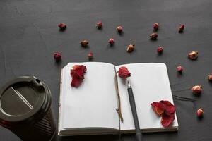 Top view of an empty notebook, scrapbook accessories and a cup of coffee on a black background. photo