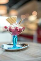 hielo crema con frambuesas en un azul vaso en un de madera mesa foto