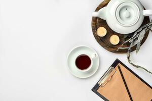 Notebook with craft paper, mobile phone, black tea, glasses on white background with copy space. photo