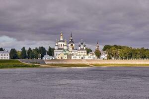 A small church and the bell tower on the banks of the river, Russia photo