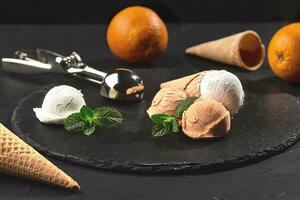 Close-up shot of a creamy and orange ice cream served on a dark slate, black background. photo