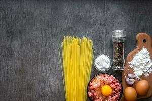 ingredientes para Cocinando pasta. espaguetis, huevos, aceituna aceite, ajo, minado carne, pimienta y Fresco apio en de madera fondo, parte superior vista, Copiar espacio foto