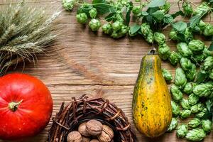 Autumn background with pumpkins, wheat spikes, nuts, vine, hops on wooden background. Top view photo