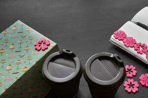 Top view of an empty notebook, scrapbook accessories and a cup of coffee on a black background. photo