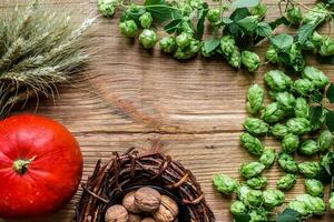 Autumn background with pumpkins, wheat spikes, nuts, vine, hops on wooden background. Top view photo