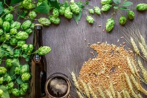 Bottle and glass beer with wheat and hops as brewing ingredients in top view and copy space area photo