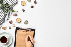 A woman hands writing on empty book note, diary, spread mockup, top view, studio. Cup of coffee break. photo