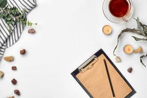 Blank opened notebook with cup of tea on white table. Top view. Writing concept photo