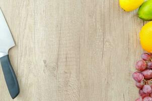 Fruits and kitchen knife on wooden table. Top view with copy space photo