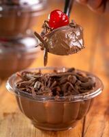 Chocolate ice cream with cherry in a glass bowl on wooden table photo