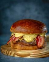hamburguesa con tocino y queso en un de madera tablero en un oscuro antecedentes foto