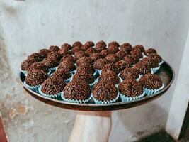 Chocolate truffles on a plate in the hands of a woman photo